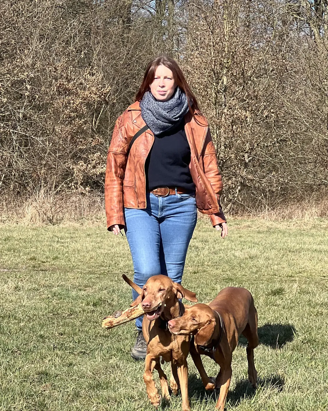 Bea Würriehausen spaziert mit ihren beiden Magyar Vizsla über eine Wiese